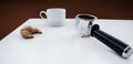 Metal holder from the coffee machine with ground coffee inside, empty coffee cup and a croissant on a white table Royalty Free Stock Photo