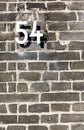 Metal House Number Fifty Four Sign On Grey Brick Wall