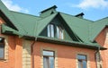 Metal house roof with attic window, roof gutters and brick walls Royalty Free Stock Photo