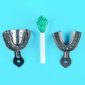 Metal impression dental spoons and green paste on a blue medical background. Human teeth care and health concept Royalty Free Stock Photo