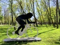 metal installation of a cyclist, lawn with green grass, bike walk in spring park