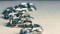 Metal iron chain slowly falls on a wooden table