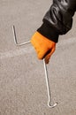 Metal jack handle in the hands of a man wearing orange gloves and a black twist