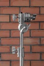Metal light stand with fastening mechanism above a red brick wall background