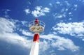 Metal lighthouse under cloudscape sky.