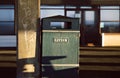 Metal litter box in the coast town. Sunlight, shadows. Defocused blurred background.