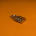 Metal lock with combination number isolated in orange background