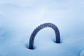 A metal loop sticking out of the snow. Part of a breakwater at the coast of Baltic sea in winter.