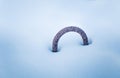 A metal loop sticking out of the snow. Part of a breakwater at the coast of Baltic sea in winter.