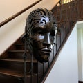 A metal mask sitting on the side of a stair case