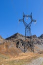 Metal mast and wires of high-voltage power line installed on slope covered with yellow autumn grass along which trail passes Royalty Free Stock Photo