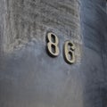 Metal material. Number eighty six (86) on a shiny glossy dark surface. Royalty Free Stock Photo