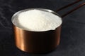 Metal measuring scoop of granulated sugar on black table, closeup Royalty Free Stock Photo