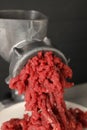 Metal meat grinder with beef mince against grey background, closeup