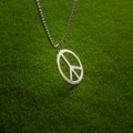 Metal medallion, with a pendant in the form of a symbol of peace on a green grass