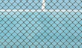 Metal Mesh fence on blurred background of blue tennis hard court Royalty Free Stock Photo