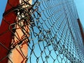 Metal mesh netting attached to a pole. Part of the fence on the sports ground. In the background is a blue sky Royalty Free Stock Photo