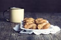 Metal mug full of coffee and a plate of koeksisters in artistic Royalty Free Stock Photo