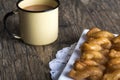 Metal mug full of coffee and a plate of koeksisters on brown woo Royalty Free Stock Photo