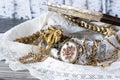Metal Open Jewelry Box with pile of golden jewelry and lace against wood background