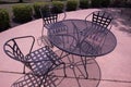 Metal outdoor dining area on sunny day with chairs and round table Royalty Free Stock Photo