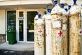 Metal oxygen tanks in front of the hospital doors. The door is marked with a sign with the inscription: