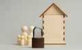 Metal padlock on the background of a wooden miniature house and wooden figures of a family on a gray background