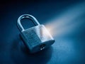 Metal padlock lying on a smooth surface illuminated by a focused beam of light symbolizing security and protection concepts in a Royalty Free Stock Photo