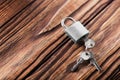 Metal padlock with silvered keys on old wooden background. Estate and security concept with symbol of protection. Royalty Free Stock Photo