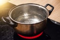 Metal pan with boiling water on the induction cooker red hot plate. Royalty Free Stock Photo