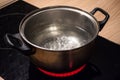 Metal pan with boiling water on the induction cooker red hot plate. Royalty Free Stock Photo