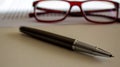 Metal pen and beautiful glasses on white document on a white table. Business concept