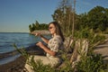 Beautiful girl playing hand pan at sunset on the sandy beach. Lovely woman resting on the shore