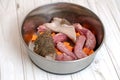 Metal pet bowl with chicken necks, beef paunch pieces and cut carrot. Royalty Free Stock Photo