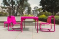 Metal pink-colored chairs on a green lawn in city park