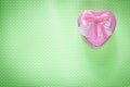 Metal pink heart-shaped gift box with ribbon on green surface ho
