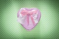 Metal pink heart-shaped present box with bow on green background
