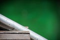 Metal pipe clamped in a mechanical vice on a green background with space for text