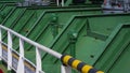 Metal pipes of green oil tanks with white railing on crude oil tanker