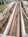 Metal pipes layed into concrete trench outdoor.
