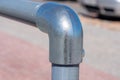 Metal pipes with rounded fastening. In the background, a light pink pavement
