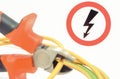 Metal pliers cut electric cable. High voltage danger sign in background. Technology concept Royalty Free Stock Photo