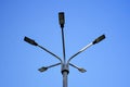 Metal pole with five modern LED lights set against clear blue sky. Street lighting. Bottom view.