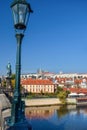 Metal pole with a lantern on the bridge and European houses on the shore with reflection