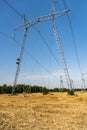 Metal poles of high-voltage power line VL-750 kV with insulators and cables in field against blue sky. Garlands of insulators Royalty Free Stock Photo