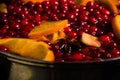 metal pot on the stove. Oranges and cranberries in mulled wine