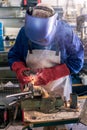 Metal processing with a man using welding machine for steel seam. Special clothe