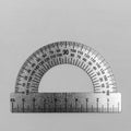 Metal protractor close-up on grey background top view, black and white