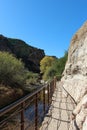 A metal railing along a trail carved into a mountainside along a creek in the mountains Royalty Free Stock Photo