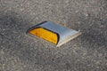 Metal road stud with yellow reflector on asphalt road in Thailand Royalty Free Stock Photo